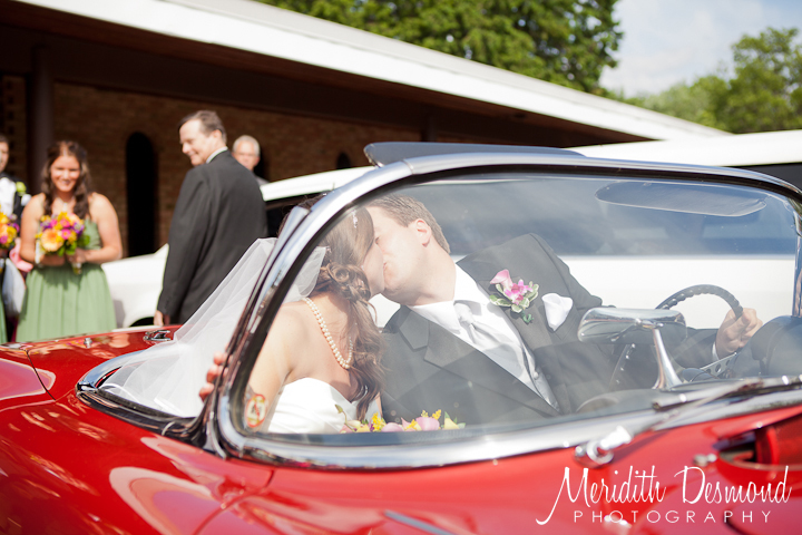 Bride and Groom kissing in a red corvette